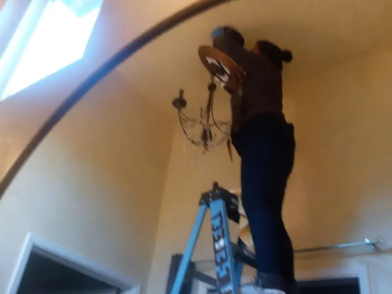 Electrician installing a chandelier in a Robinson residence